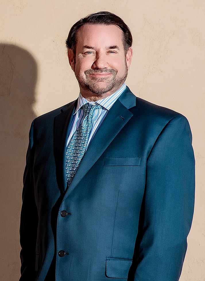 Man in suit smiling against a neutral background