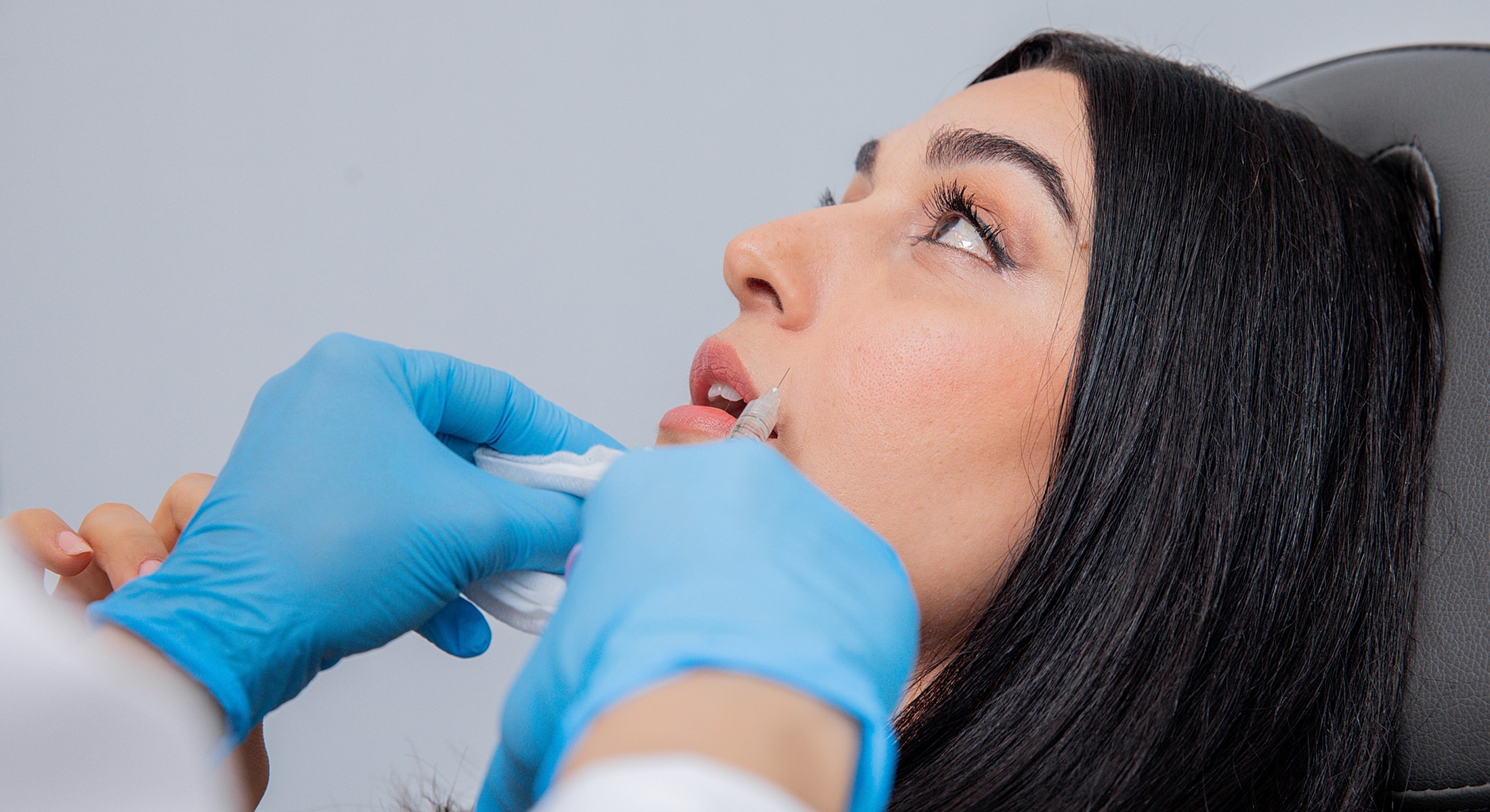 Patient receiving cosmetic lip treatment in clinic.