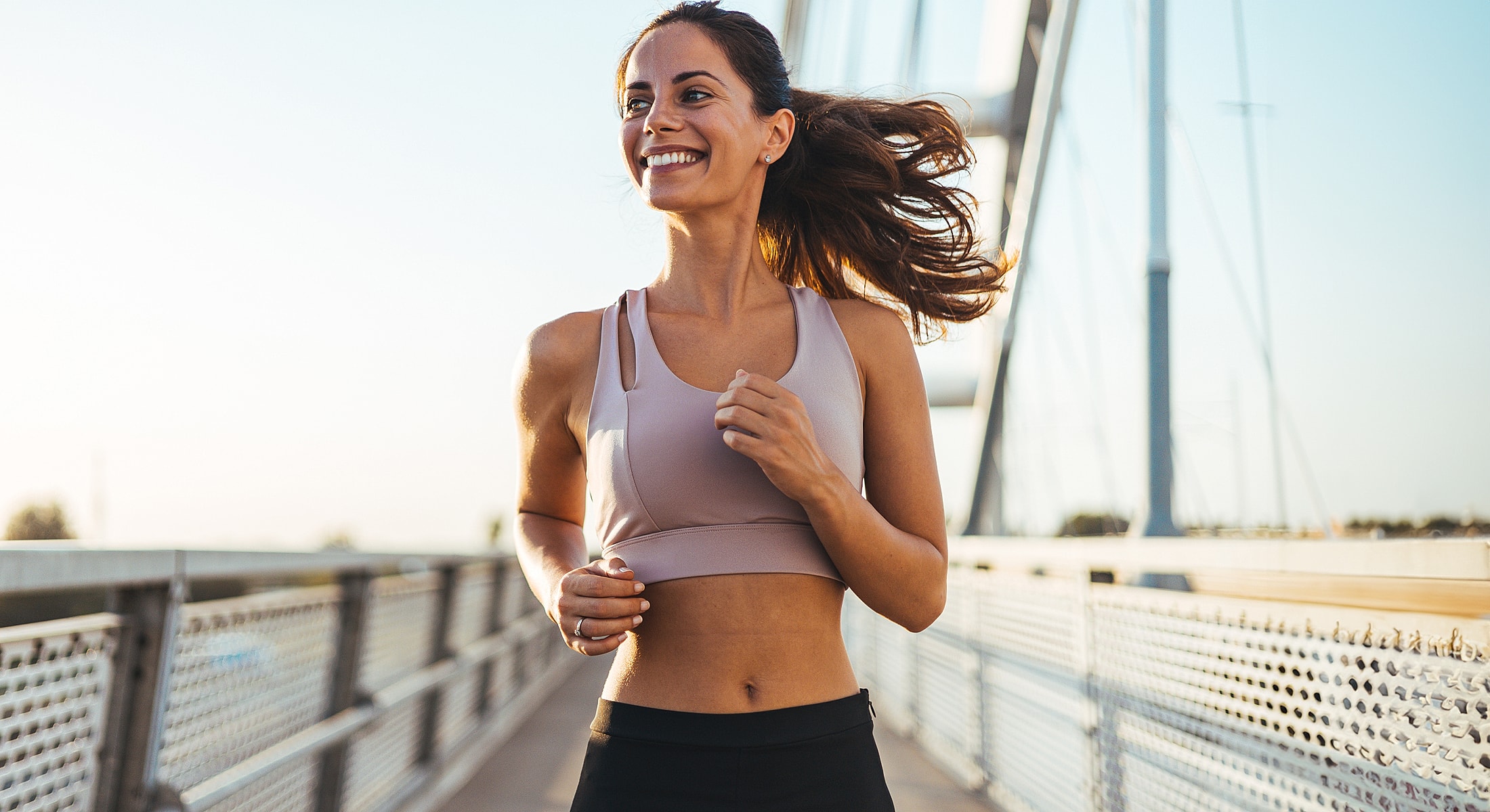 Woman jogging on a bridge during sunset.