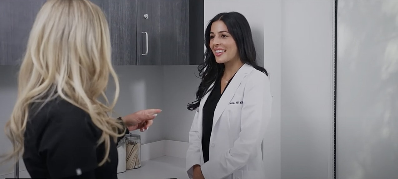Woman speaking with plants and flowers behind her.