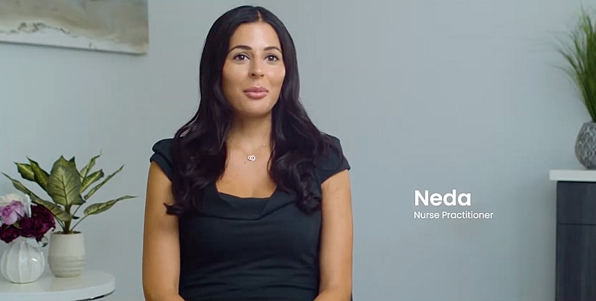 Woman speaking with plants and flowers behind her.