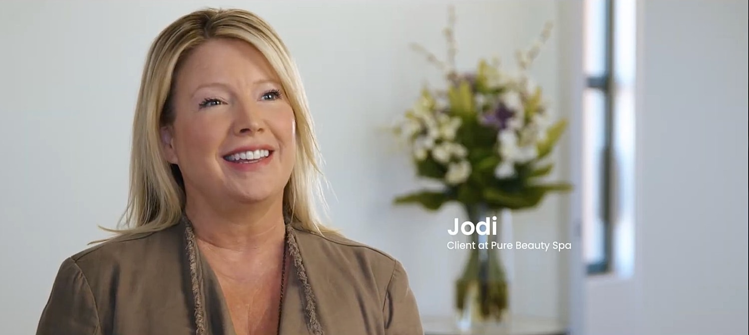 Woman speaking with plants and flowers behind her.